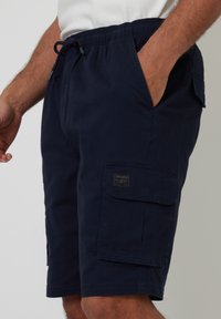 Marineblaue Cargo-Shorts aus strapazierfähigem Material, mit elastischem Bund und Kordelzug, seitlichen Taschen und einer aufgesetzten Tasche am Bein.