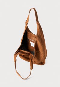 Bruine suède tote bag met een enkele schouderband, brede opening en een zwart gevoerd interieur met een ritsvak en een insteekvak.