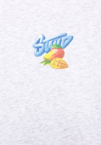 Testo "STEP" blu sopra un mango maturo con foglie verdi e un pezzo di mango affettato su uno sfondo di tessuto grigio chiaro.