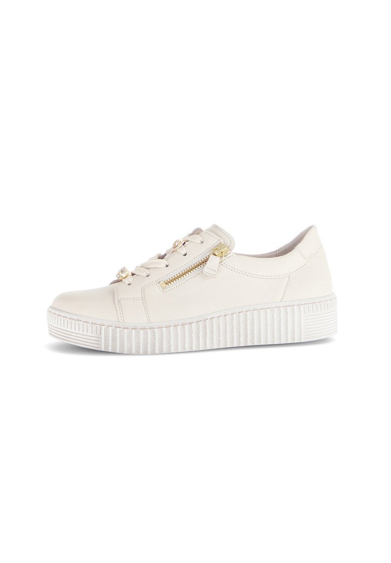 Crème-kleurige casual sneaker met een dikke ribbelzool, een zijrits en vetersluiting met gouden hardware, geïsoleerd op een witte achtergrond.