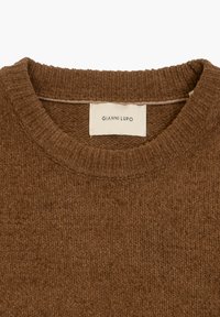Brązowy dzianinowy sweter z okrągłym dekoltem, z wyraźnym wzorem teksturowym oraz metką z napisem "Gianni Lupo" wewnątrz kołnierza.