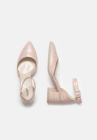 Scarpe con tacco a blocco in pelle verniciata beige, con punta affusolata, cinturino alla caviglia e motivo in texture coccodrillo. Fodera interna liscia.
