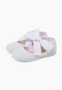 Bailarinas de tela blanca con un upper texturizado, punta redondeada y un gran lazo blanco en la parte delantera. Suela blanda para mayor comodidad.