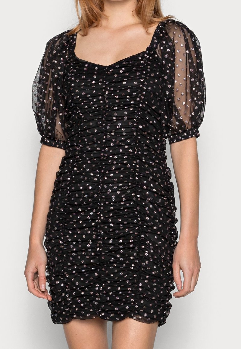 Svart rynkad klänning med genomskinliga puffärmar, prydd med silverfärgade blommönster. Har en fyrkantig halsringning och strukturerad tyg.