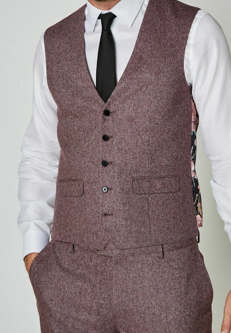 Gilet en tweed violet avec une fermeture à cinq boutons, des poches latérales et une doublure à motif floral. Porté sur une chemise blanche et une cravate noire.