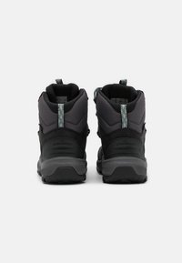 Botas de senderismo negras con parte superior de tejido texturizado, talón reforzado y suela de goma resistente. Incluyen acentos reflectantes y una asa de agarre.