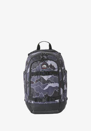 Mochila con patrón de montaña gris y negro, dos correas delanteras con hebilla, bolsillos laterales y asa superior para llevar.