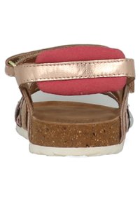 Roze gouden sandaal met zachte roze achterkant, kurken zool en witte buitenzool. Voorzien van een verstelbare band om de enkel en een geweven ontwerp.