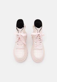 Bottes chevilles rose clair avec une texture crocodile, dotées de lacets ruban et de fermetures éclair latérales, sur une semelle épaisse avec un design à plateforme.