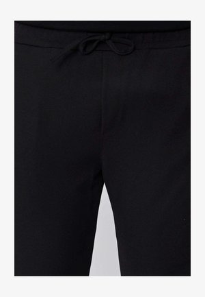 Pantalon noir avec une taille à cordon de serrage noué et un devant en tissu lisse et uni.