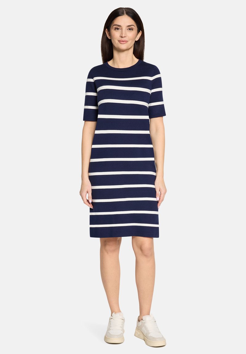 Robe à manches courtes à rayures bleu marine et blanc, en tissu doux. Elle présente une silhouette droite, longueur au genou, portée avec des baskets légères.