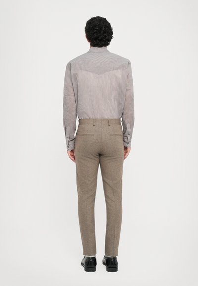 Chemise rayée grise et blanche avec un col haut et des poignets boutonnés, assortie à un pantalon marron ajusté ; texture lisse, design cintré.
