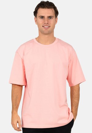 Rosa Baumwoll-T-Shirt mit Rundhalsausschnitt und kurzen Ärmeln. Verfügt über einen lässigen Schnitt und eine glatte Textur. Schlichtes Design ohne Muster.