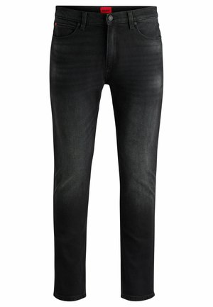 Jeans de mezclilla negra con un corte ajustado, bolsillos delanteros y cierre de botón. Presentan un desvanecimiento sutil y una etiqueta de logo roja en la cinturilla.