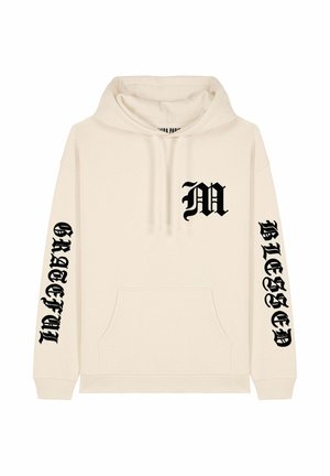 Crème hoodie met een buidelzak, zwarte tekstontwerp met de letter "M" op de borst, en "GRATEFUL" en "BLESSED" op de mouwen.