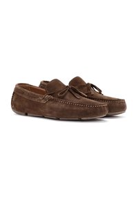Mocasines de ante marrón con puntas redondeadas, con costuras decorativas a lo largo de los lados y lazos decorativos en la parte frontal. Suelas de goma planas.