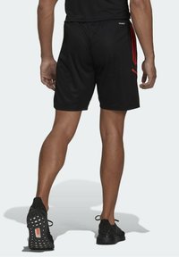 Svarta sportshorts med röda detaljer, elastiskt midjeband och ett lätt, andningsbart material. Svarta löparskor med texturerade sulor.