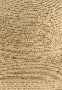 Słomkowy kapelusz w naturalnym beżowym kolorze, z teksturowanym wzorem plecionki oraz koronką wplecioną wokół korony.