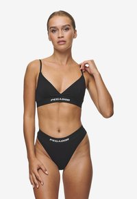 Bikini noir avec un soutien-gorge triangular à fines bretelles et un bas taille haute. Les deux pièces ont une bande logo blanche "PEGADOR".