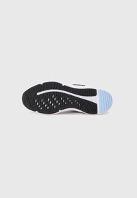 Semelle d'une sneaker avec un motif noir, une semelle intermédiaire blanche et un détail en caoutchouc bleu clair sur le talon, sur un fond blanc uni.