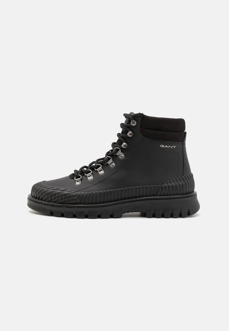 Botte de randonnée noire montante avec semelle épaisse à crampons, œillets métalliques, col rembourré et logo GANT sur le côté.