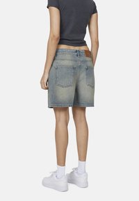 Shorts in denim di un colore azzurro chiaro sbiadito, con un design a cinque tasche, yoke posteriore e un contrassegno in pelle marrone contrastante in vita.