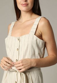 Robe en lin de couleur claire avec un décolleté carré, de larges bretelles, des rayures verticales, des boutons sur le devant et un détail à la taille nouée.