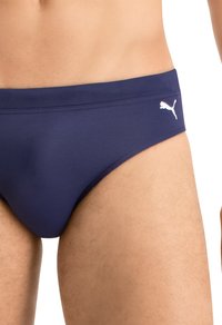 Marineblaue Badeunterhose aus glattem synthetischem Material, mit einem weißen Puma-Logo auf der linken Seite und einem klassischen, minimalistischen Design.