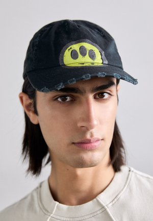 Casquette de baseball noire avec une visière usée et un graphique circulaire jaune vif accompagné de trois points noirs. Design plat et décontracté.