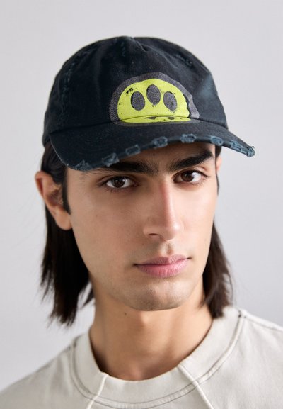 Cappellino da baseball nero con visiera consumata e una grafica circolare gialla brillante con tre punti neri. Design piatto e casual.