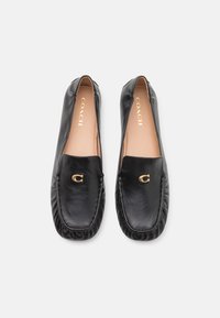 Sorte læderslippers med rund tå, prydet med en gylden logoaccent og bløde sømme langs kanterne. Flad sål.
