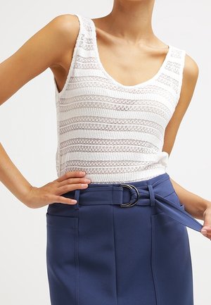 Valkoinen neulottu tankkitoppi, jossa on pyöreä pääntie ja vaakaraidallinen kuvio, yhdistetty korkeavyötäröiseen siniseen hameeseen, jossa on vyö ja lenkit.