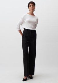 Witte lange mouwen top, gecombineerd met hoogwaisted zwarte broek met krijtstrepen en zwarte spitse hakken, met een relaxte pasvorm en klassiek ontwerp.