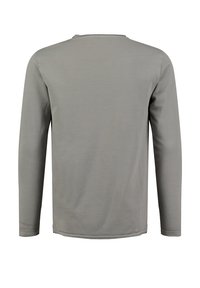 Langarmshirt in Hellgrau, aus einem glatten Stoff gefertigt. Rundhalsausschnitt mit einfachem Design und Nahtdetails entlang des Saums und der Ärmel.