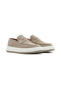 Beige suede slip-on shoes with a simple design, featuring a raised seam and rubber sole, accented by a white midsole and grey outsole.