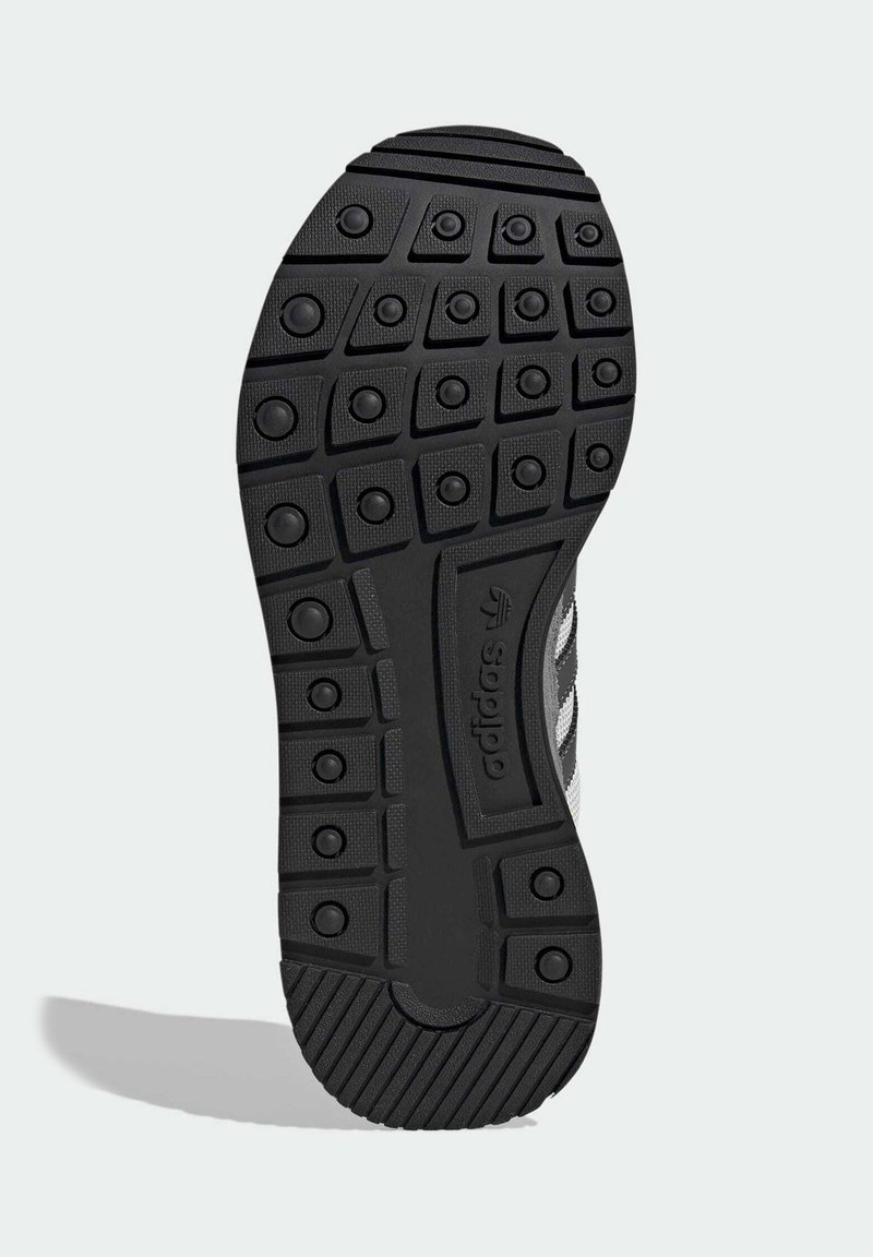 Svart gummisula med texturerat mönster, som har cirkulära och kantiga grepp samt en sektion med en präglad logotyp.