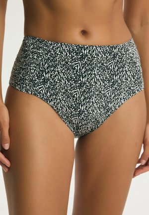 Bikinihose mit hoher Taille und schwarz-weißem abstraktem Tiermuster, getragen von einer stehenden Person vor neutralem Hintergrund.