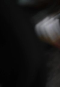 Blurry image of a ceramic mug with a white and orange gradient, smooth texture, and rounded shape against a dark background.