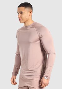 Langärmliges Sportshirt aus leichtem rosa Stoff, mit gerippter Textur und seitlichem Branding-Detail, einem runden Ausschnitt und figurbetonter Passform.