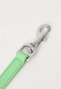 Cinturino in pelle verde con superficie testurizzata, dotato di una clip e accessori in metallo argento per un attacco sicuro.