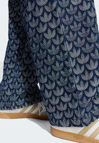 Džínsové nohavice s kvetinovým vzorom v modrých a sivých odtieňoch. Nohavice majú široké nohy s detailným prešitím. Kombinované s bielymi teniskami.