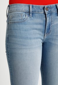 Ljusblå denimjeans med slim fit, med framfickor, midja med bälteshällor och subtil blekt textur.