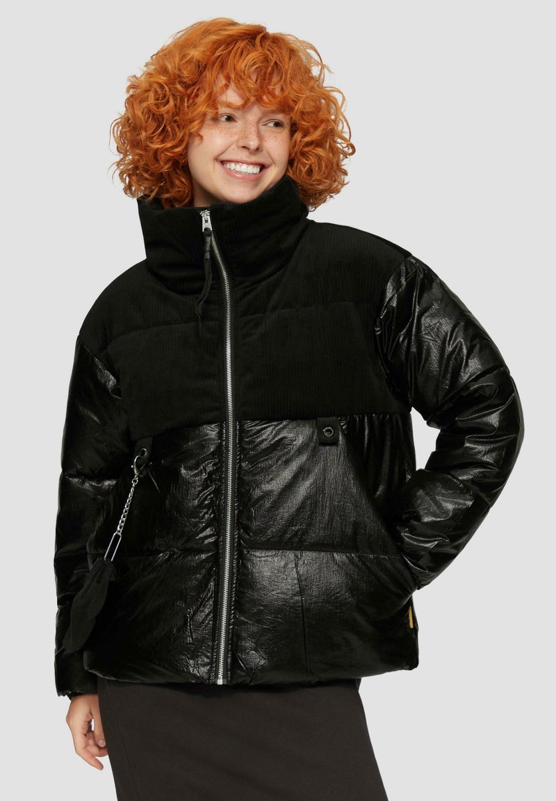 Zwarte pufferjack met hoge kraag; heeft een mix van glanzend en textuurmateriaal, ritsopening en zijvakken.