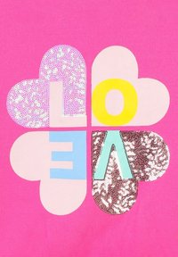 Tissu rose avec un motif en forme de cœur comportant des lettres en sequins épelant "AMOUR" dans différentes couleurs : jaune, bleu et argenté, avec une finition texturée.