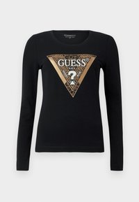 Maglietta nera a maniche lunghe con triangolo dorato e stampa leopardata che presenta la parola "GUESS" e un punto interrogativo al centro.