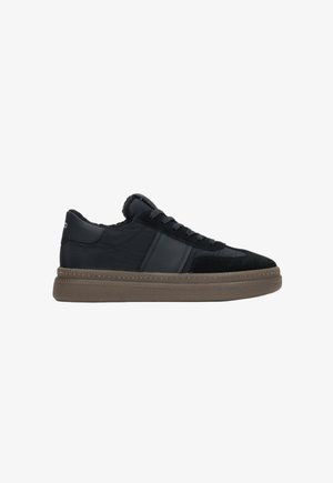 Schwarzer Sneaker aus Wildleder und Leder, mit runder Zehenpartie, gepolsterter Knöchelpartie und einer strukturierten braunen Gummisohle. Minimalistisches Design mit kontrastierenden Akzenten.