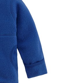 Ärmel einer blauen Fleecejacke mit weichem Material, abgerundeten Nähten und einem verstellbaren Bündchen mit einem dezenten Taschen-Detail.