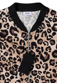 Veste zippée à imprimé léopard avec col et poignets noirs, fond beige, étiquette de marque visible avec l'inscription "Cecil" à l'intérieur du col.