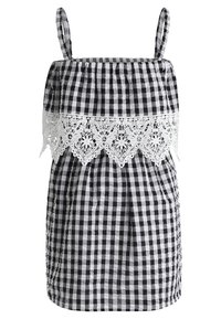 Musta-valkoinen gingham-kuviollinen mekko, jossa on kerääntynyt yläosa, pitsireunus ja säädettävät olkaimet. Materiaali on kevyt ja kudottu.