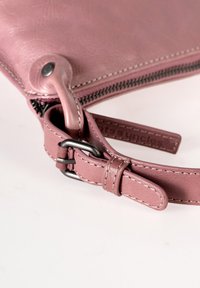 Borsetta in pelle rosa con finitura texturizzata, una cerniera metallica e una tracolla removibile con fibbia in argento e dettagli di cucitura.